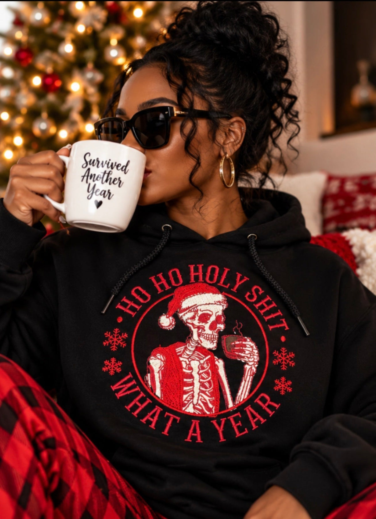 Black woman wearing holiday skeleton embroidered hoodie in cozy Christmas living room